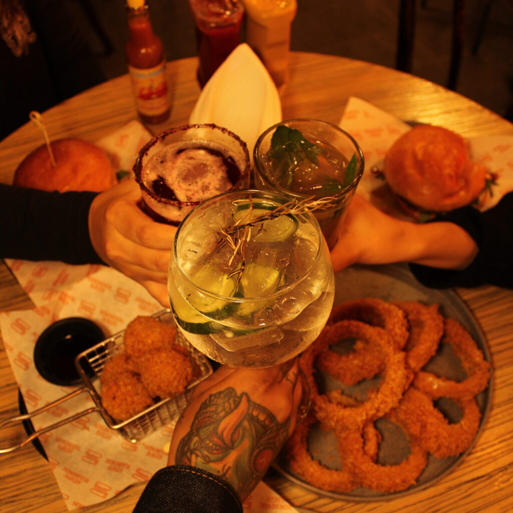 Amigos brindando y disfruando de hamburguesas gourmet en cdmx, en Monumental Burger.